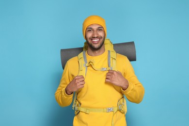 Happy tourist with backpack on light blue background