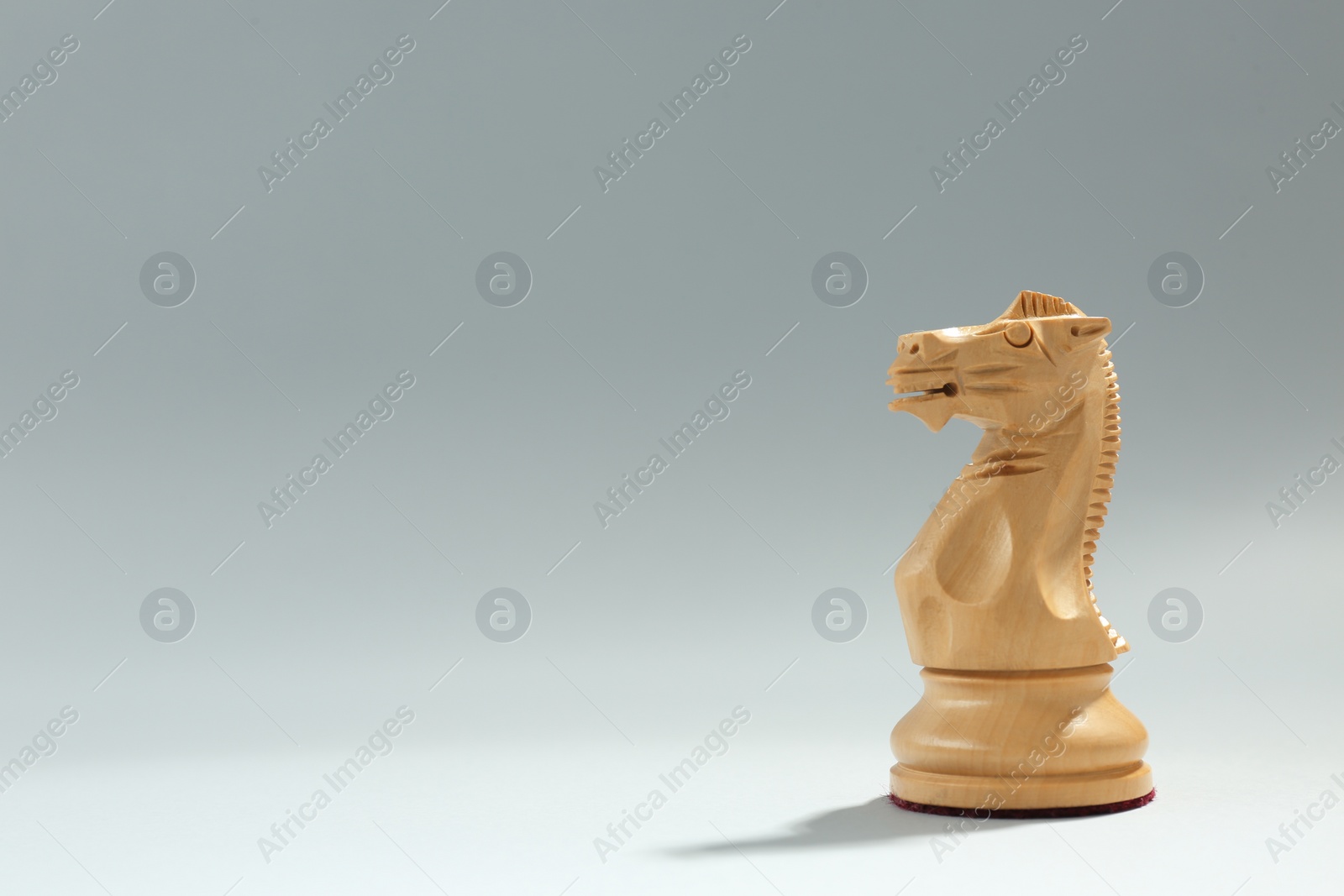 Photo of Wooden knight on light background, space for text. Chess piece