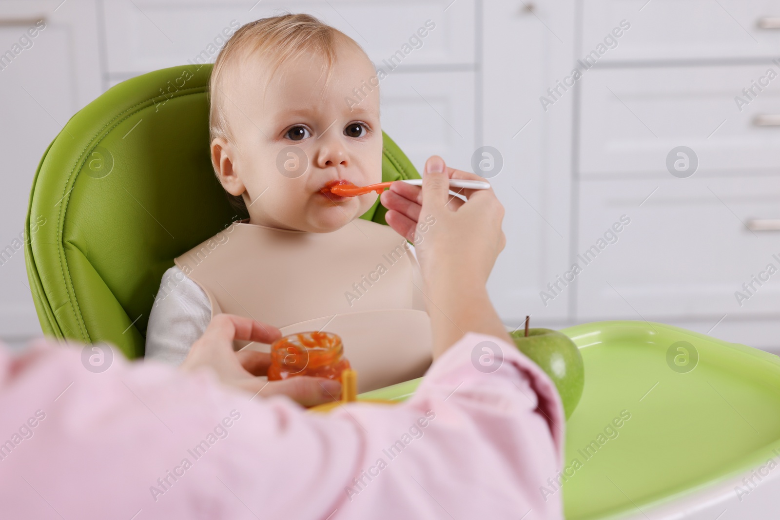 Photo of Mother feeding her cute little baby with healthy food at home