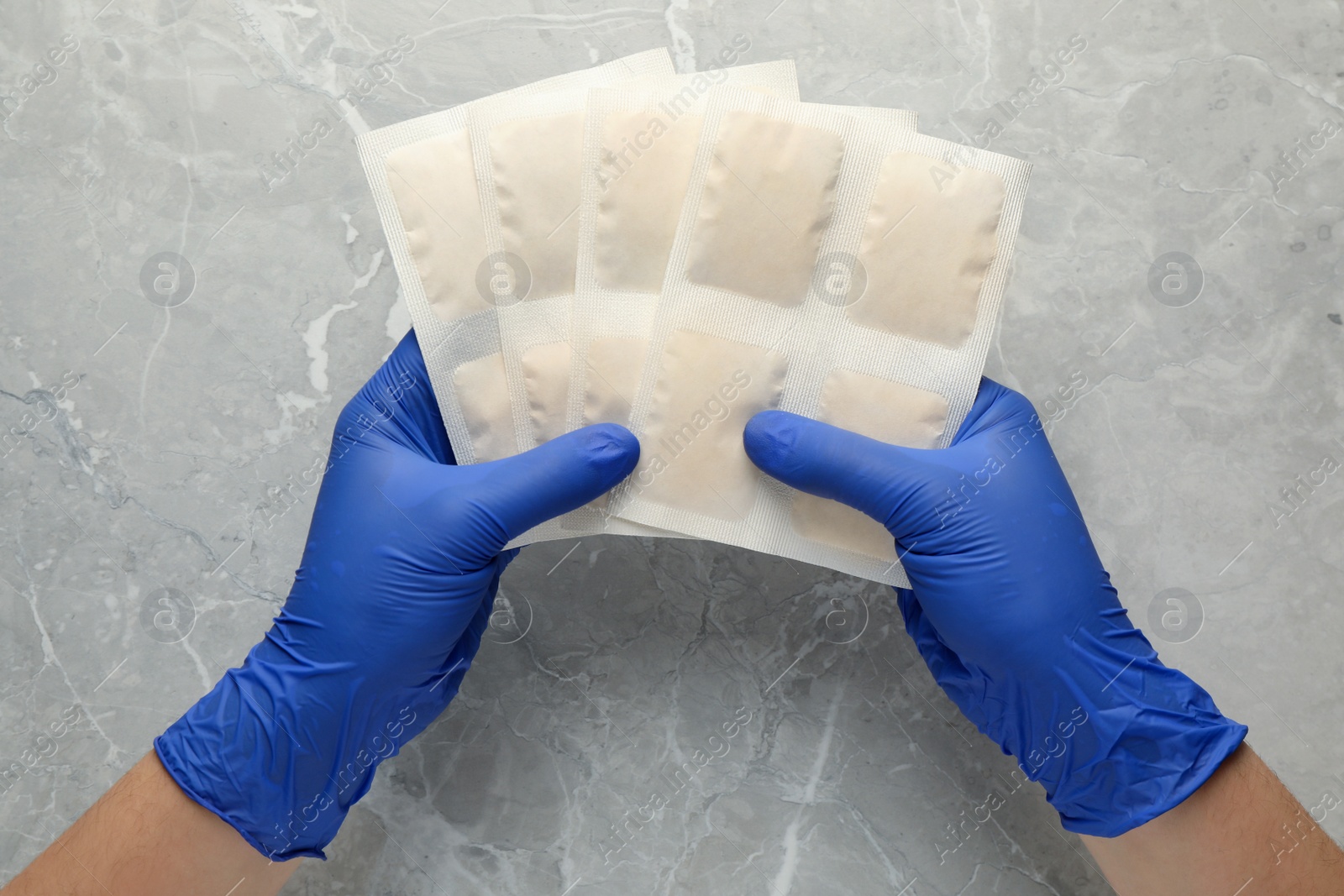 Photo of Man in gloves with mustard plasters at light grey marble table, top view