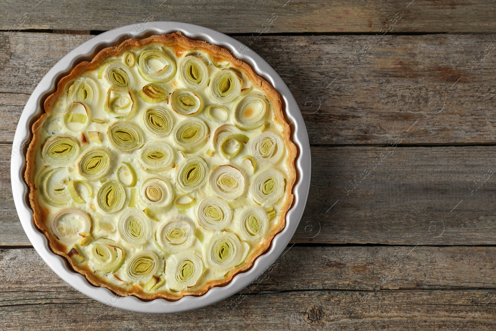 Photo of Tasty leek pie on old wooden table, top view. Space for text