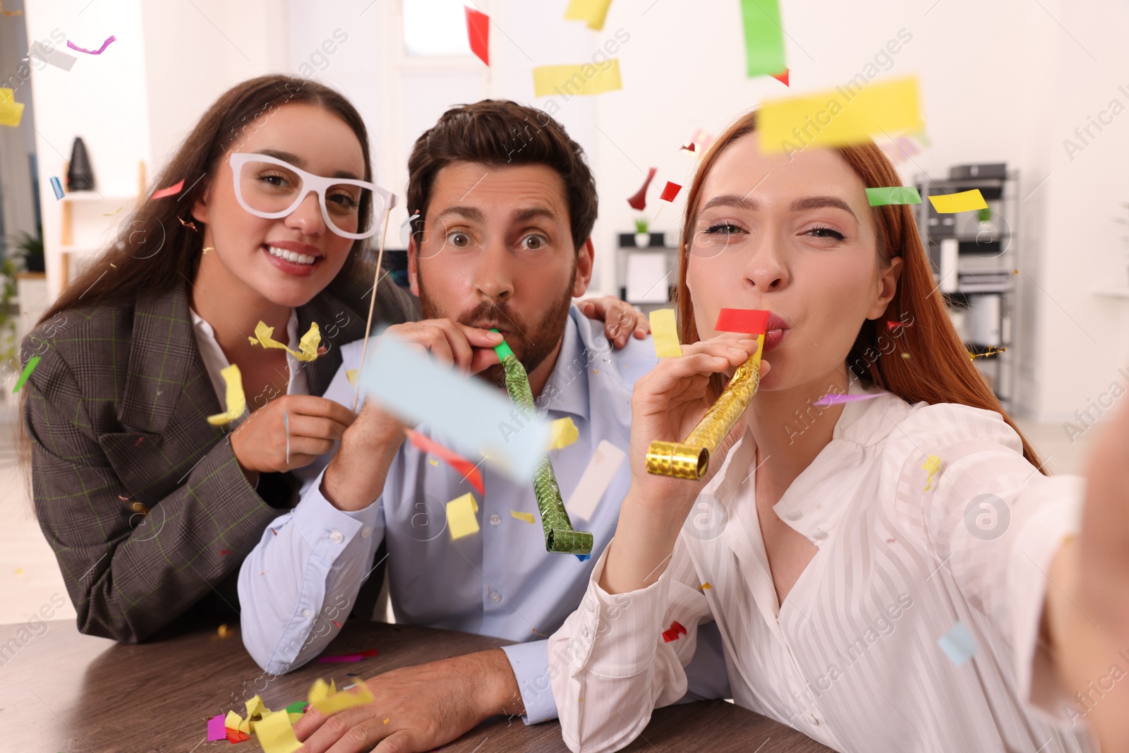 Photo of Coworkers taking selfie during office party indoors