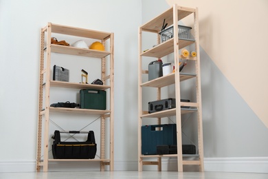 Wooden shelving units with different instruments near color wall. Stylish room interior