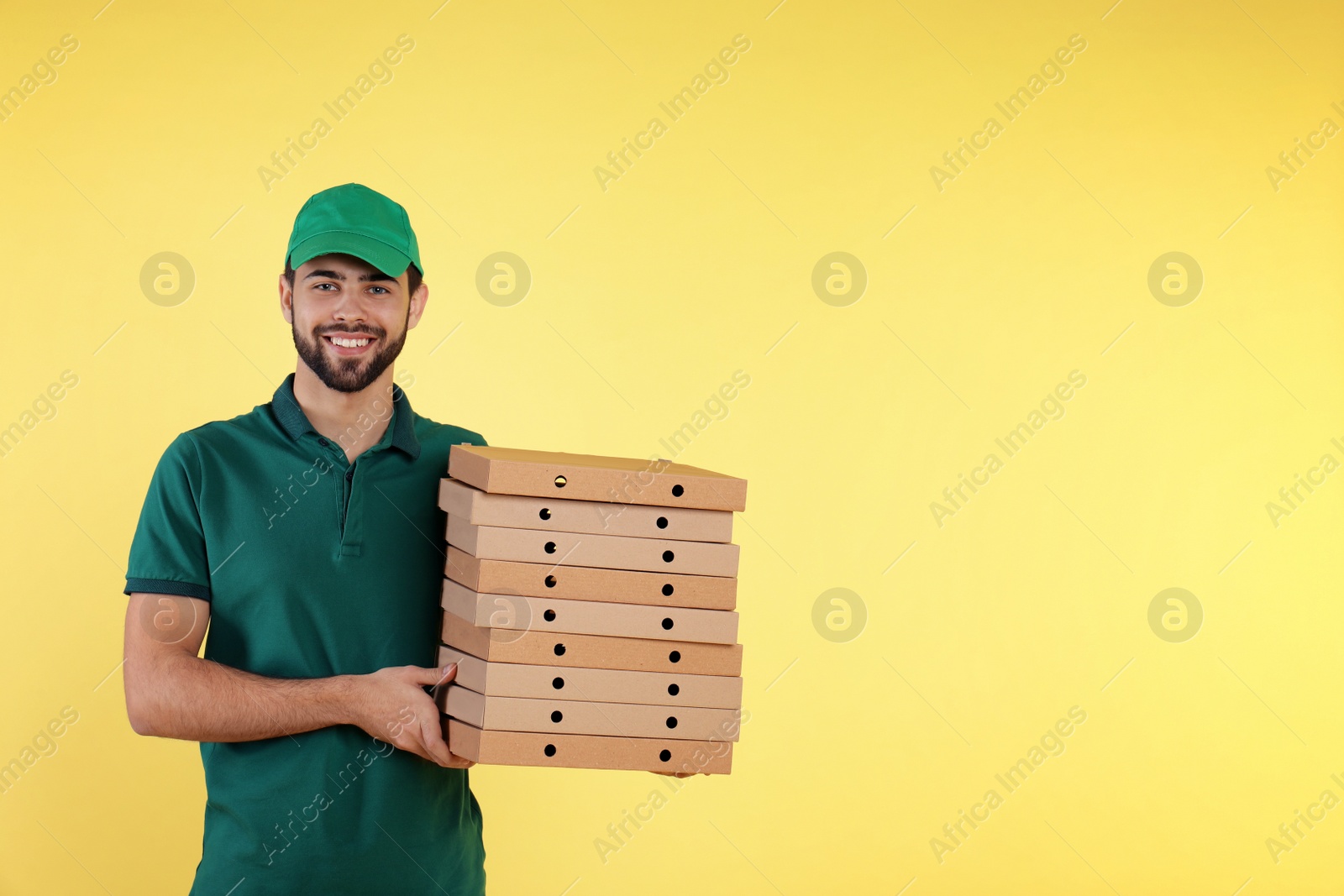 Photo of Young courier with pizza boxes on color background, space for text. Food delivery service