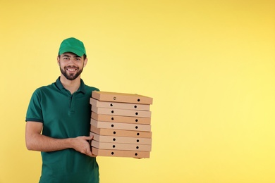 Young courier with pizza boxes on color background, space for text. Food delivery service