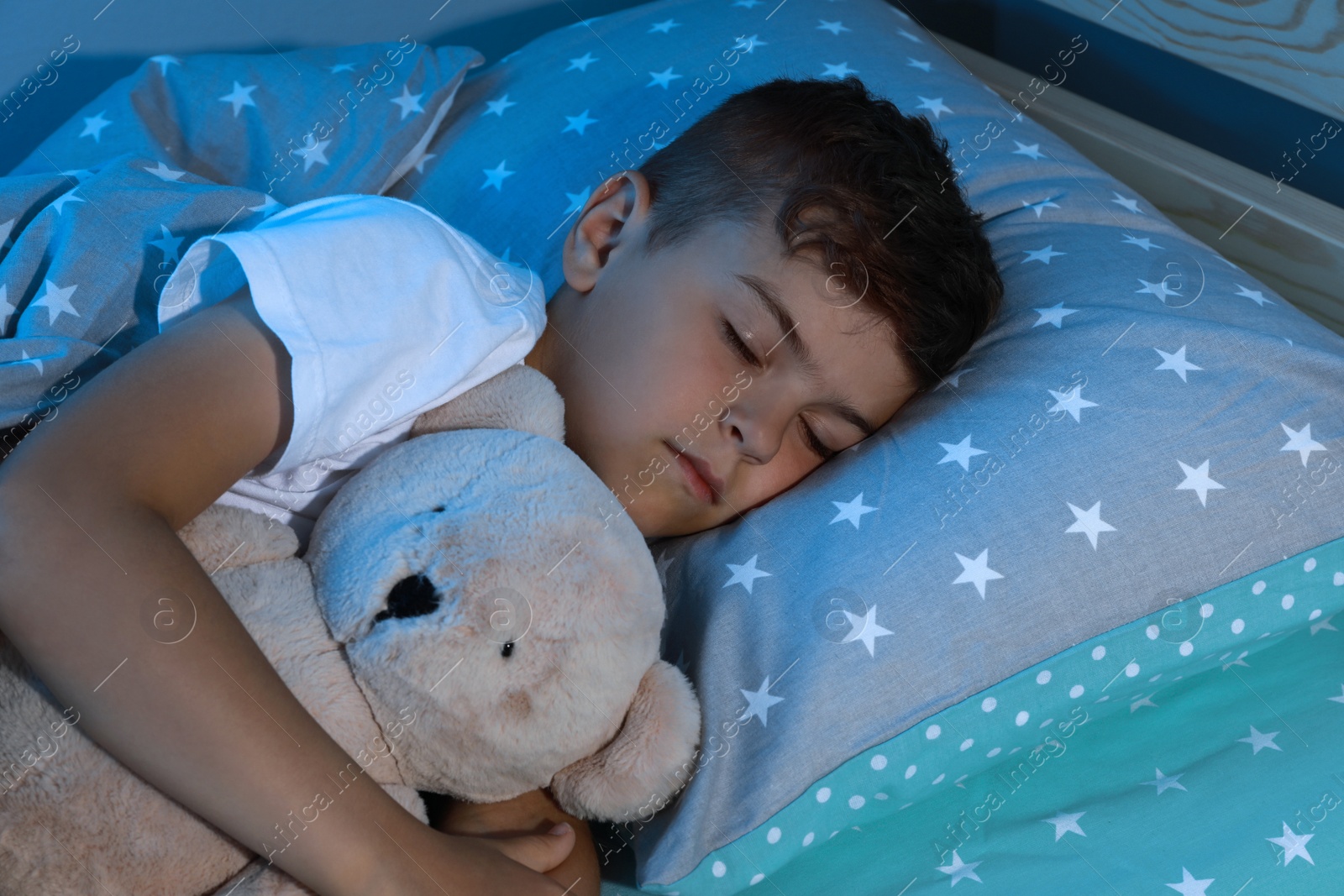 Photo of Cute little boy sleeping with teddy bear at home. Bedtime