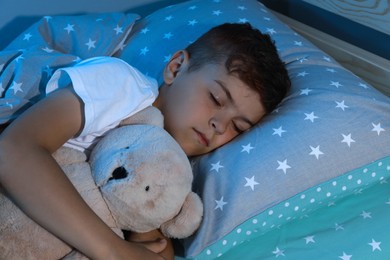 Photo of Cute little boy sleeping with teddy bear at home. Bedtime