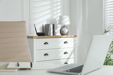 Photo of Modern wi-fi router on chest of drawers indoors