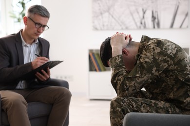 Photo of Professional psychotherapist working with military man in office