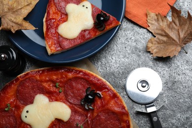 Cute Halloween pizza with ghosts and spiders served on grey table, flat lay