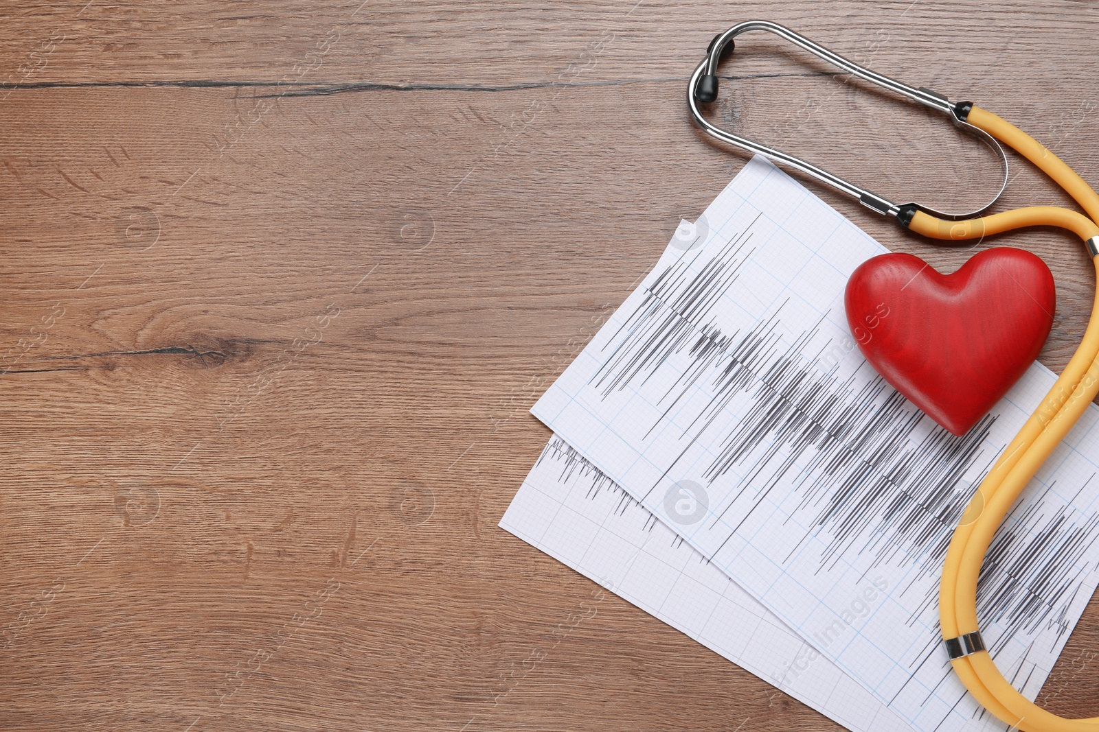 Photo of Stethoscope, red heart and cardiogram on wooden table, flat lay with space for text. Cardiology concept