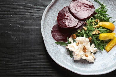 Plate with delicious beet salad on wooden background, top view