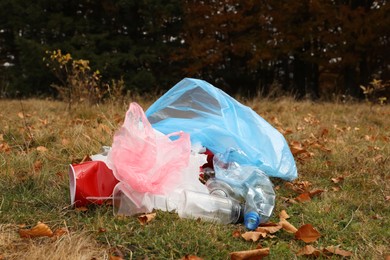 Pile of plastic garbage on grass near forest