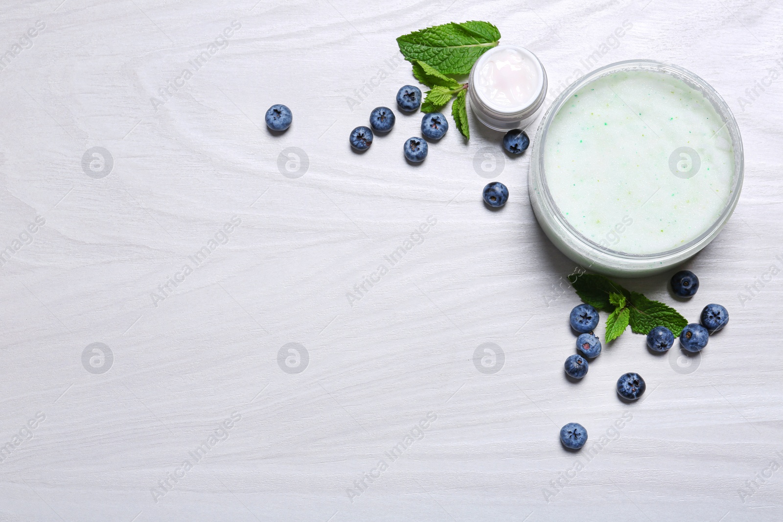 Photo of Flat lay composition with jars of body cream on light wooden background. Space for text