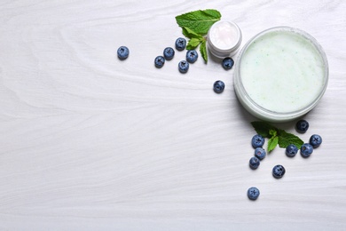 Photo of Flat lay composition with jars of body cream on light wooden background. Space for text