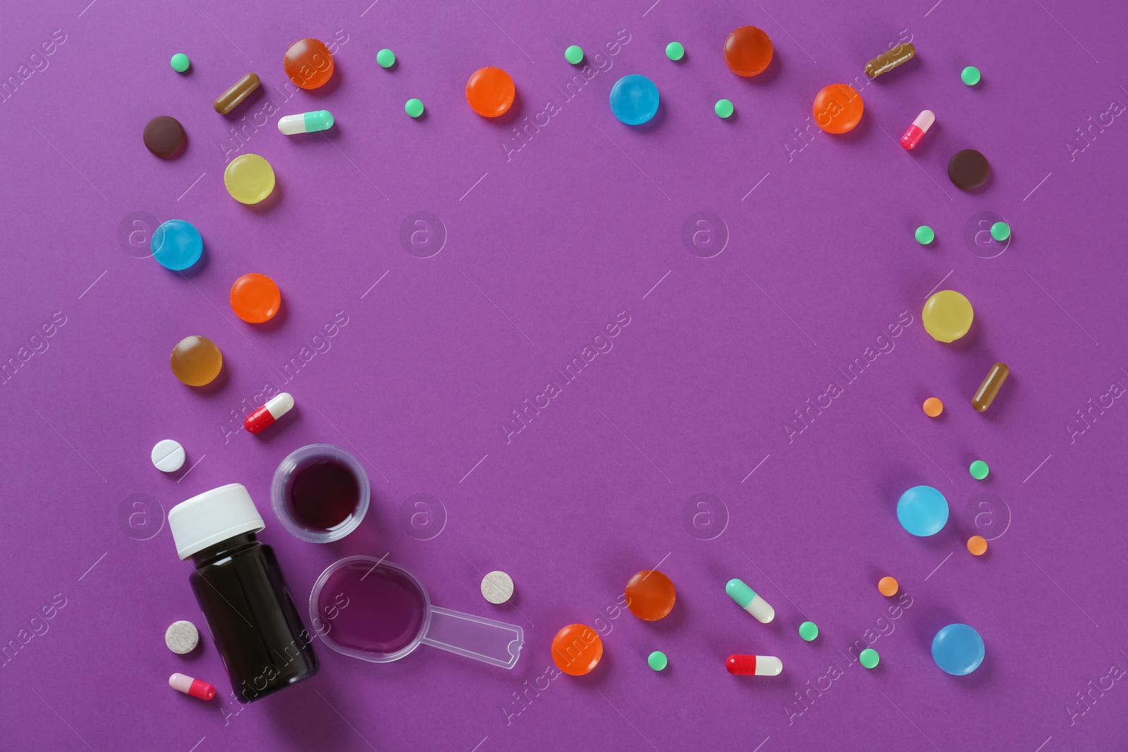 Photo of Frame made with cough drops, syrup and pills on purple background. Space for text