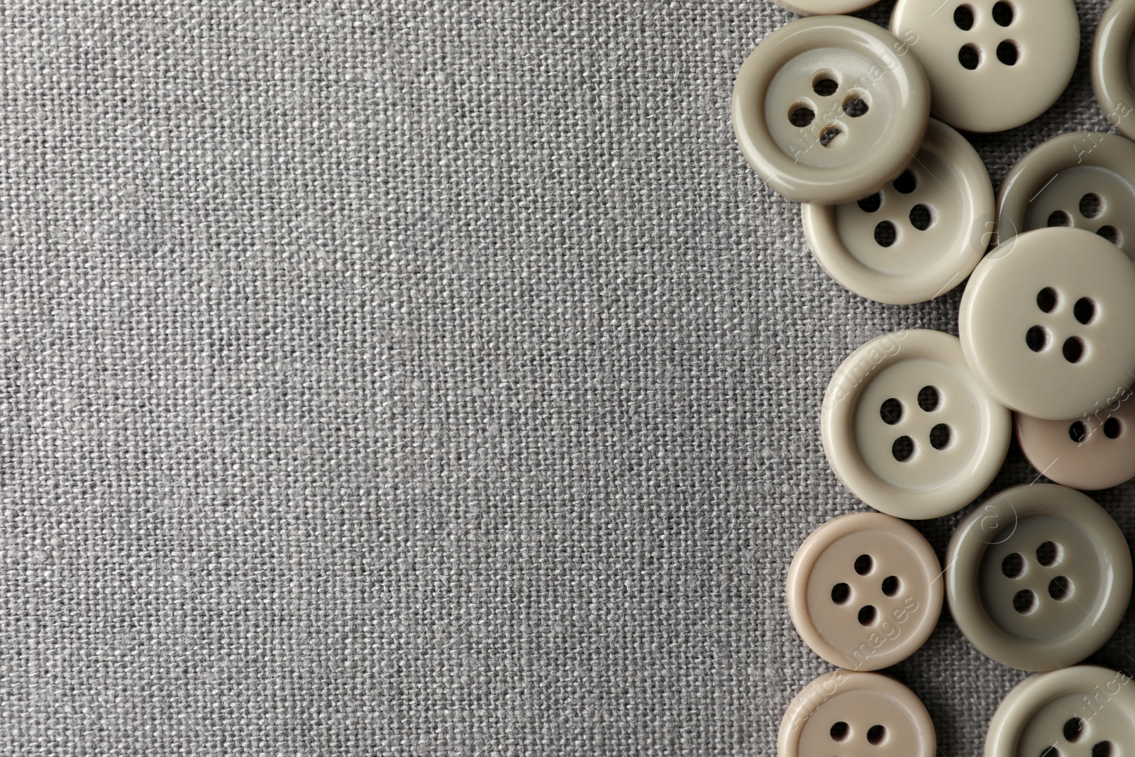 Photo of Many plastic sewing buttons on grey fabric, flat lay. Space for text