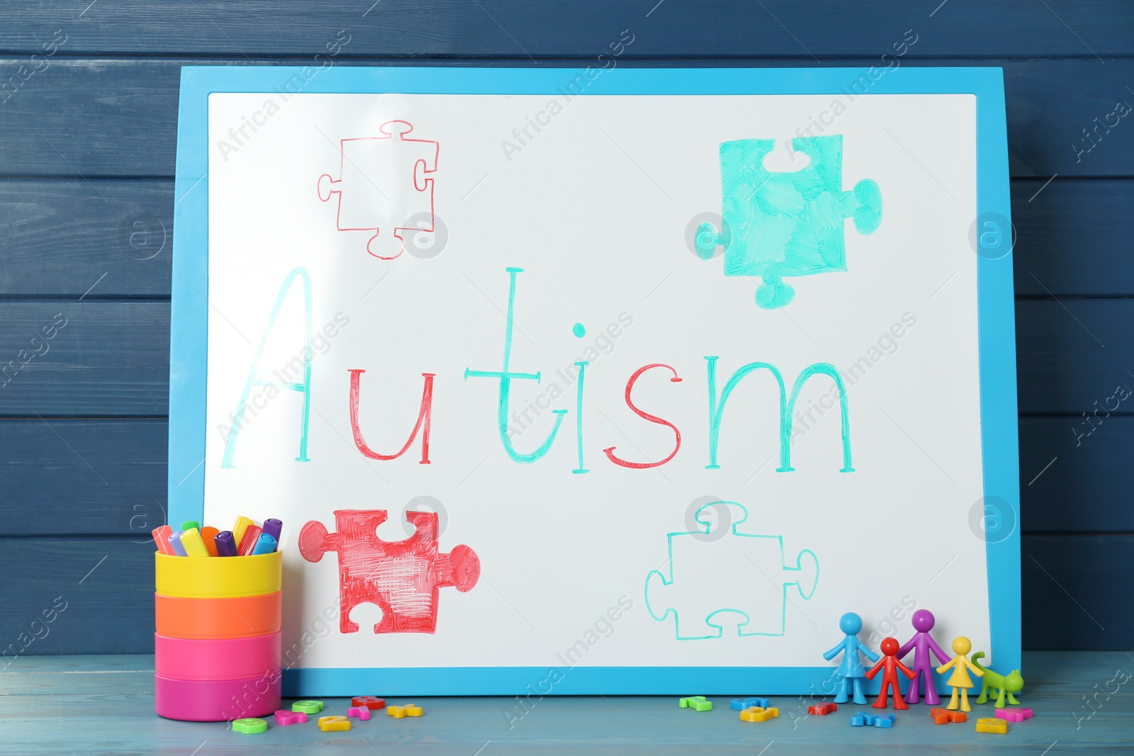 Photo of MYKOLAIV, UKRAINE - DECEMBER 30, 2021: White board with word Autism, stationery and toys on light blue wooden table