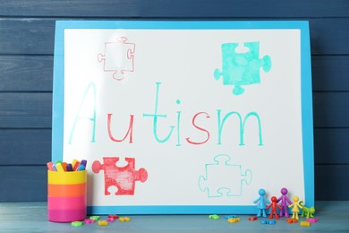 MYKOLAIV, UKRAINE - DECEMBER 30, 2021: White board with word Autism, stationery and toys on light blue wooden table