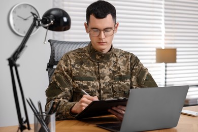 Military service. Young soldier working at table in office