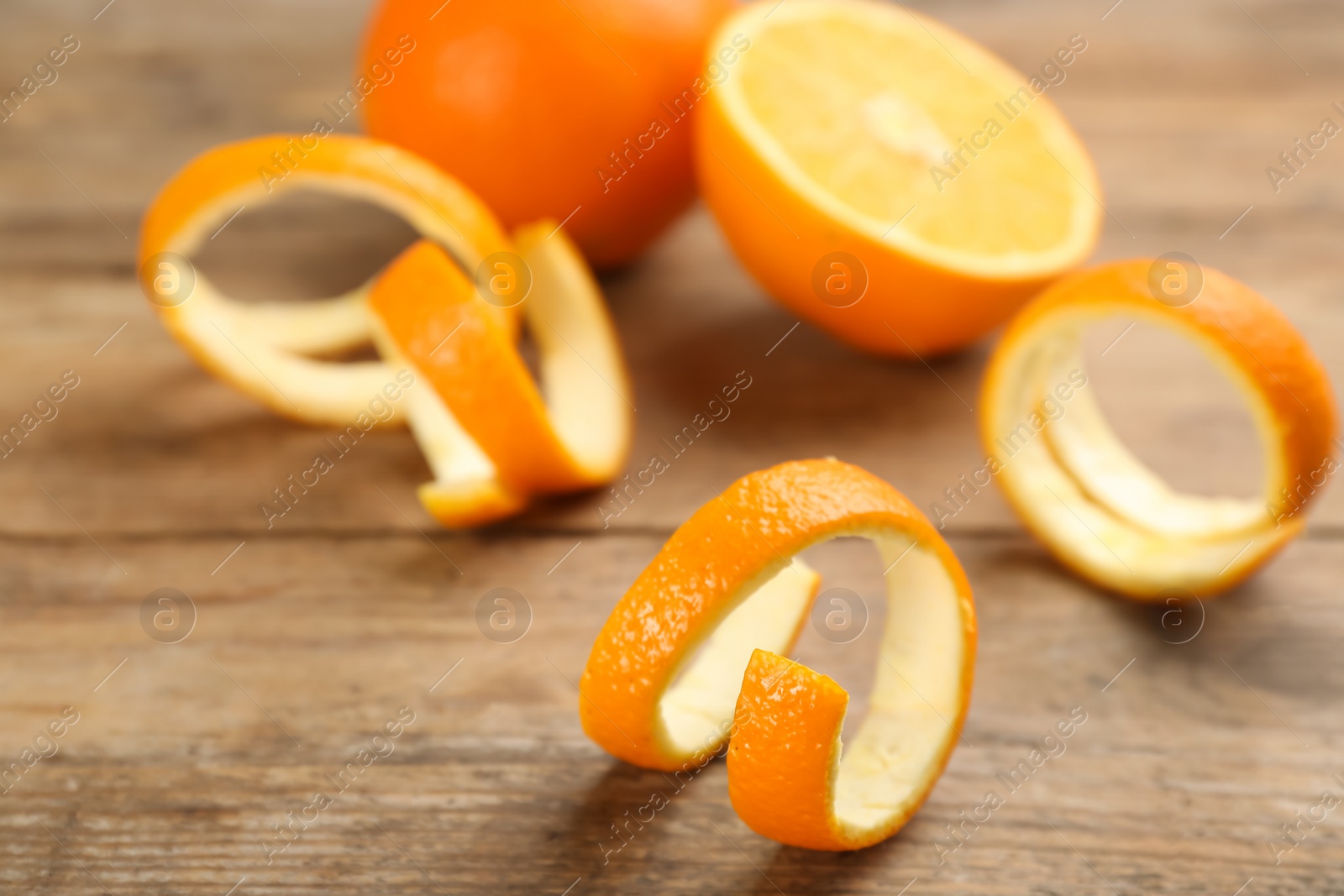 Photo of Fresh spiral orange peels on wooden table