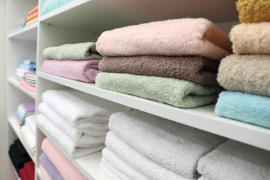Photo of Different terry towels on shelves in linen shop