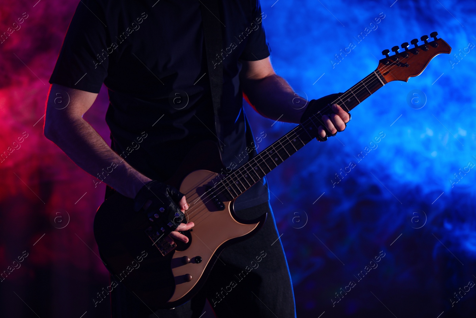 Photo of Man playing electric guitar on stage, closeup. Rock music