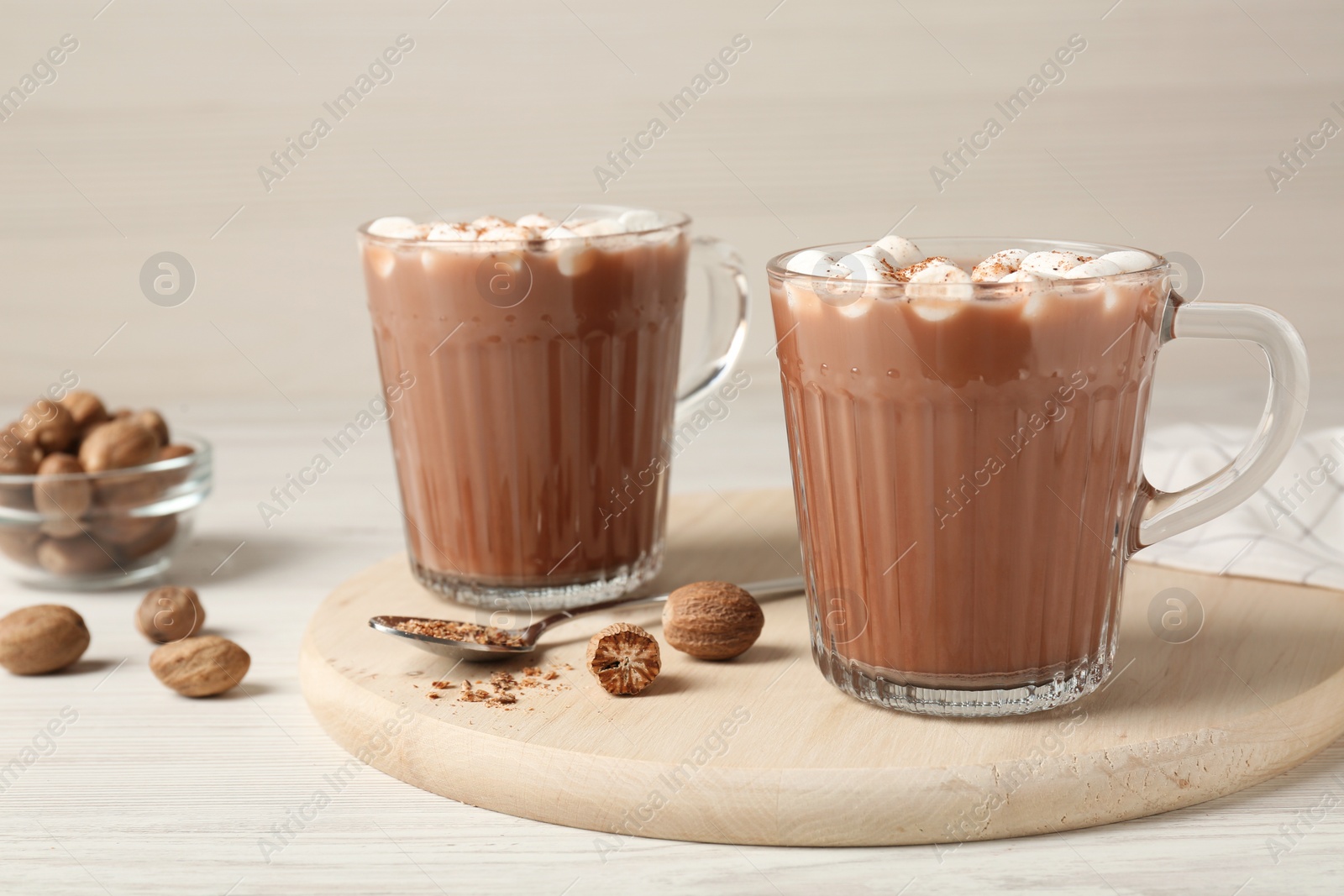 Photo of Cocoa drink with nutmegs and marshmallows on white wooden table