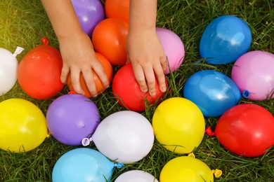 Photo of Top view of little kid with water bombs on green grass