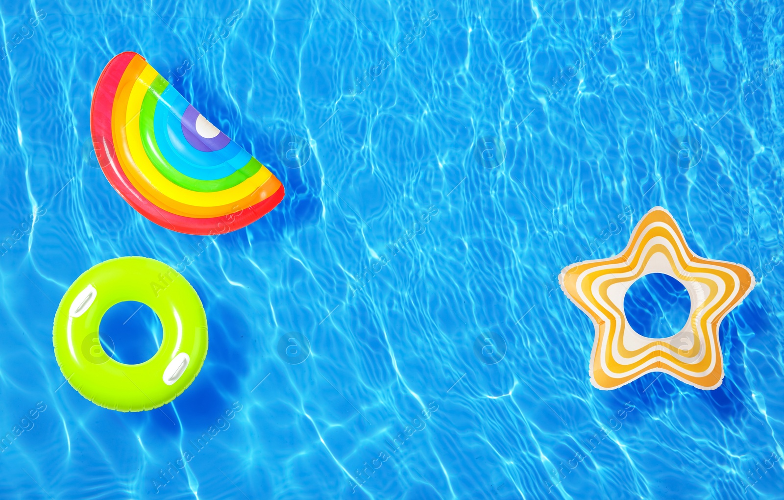 Image of Different inflatable rings floating in swimming pool, top view