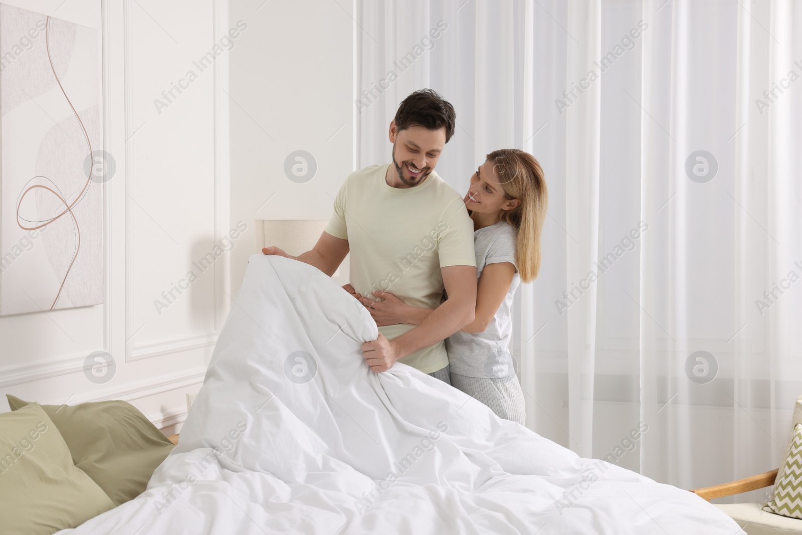 Photo of Couple changing bed linens at home. Domestic chores