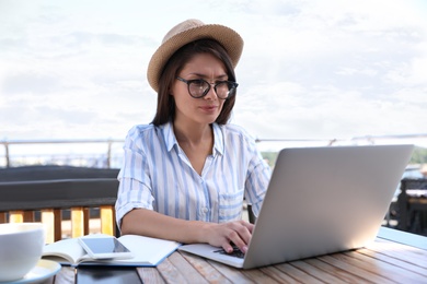 Beautiful woman with glasses using laptop at outdoor cafe
