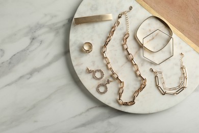 Photo of Stylish golden bijouterie on white marble table, top view. Space for text