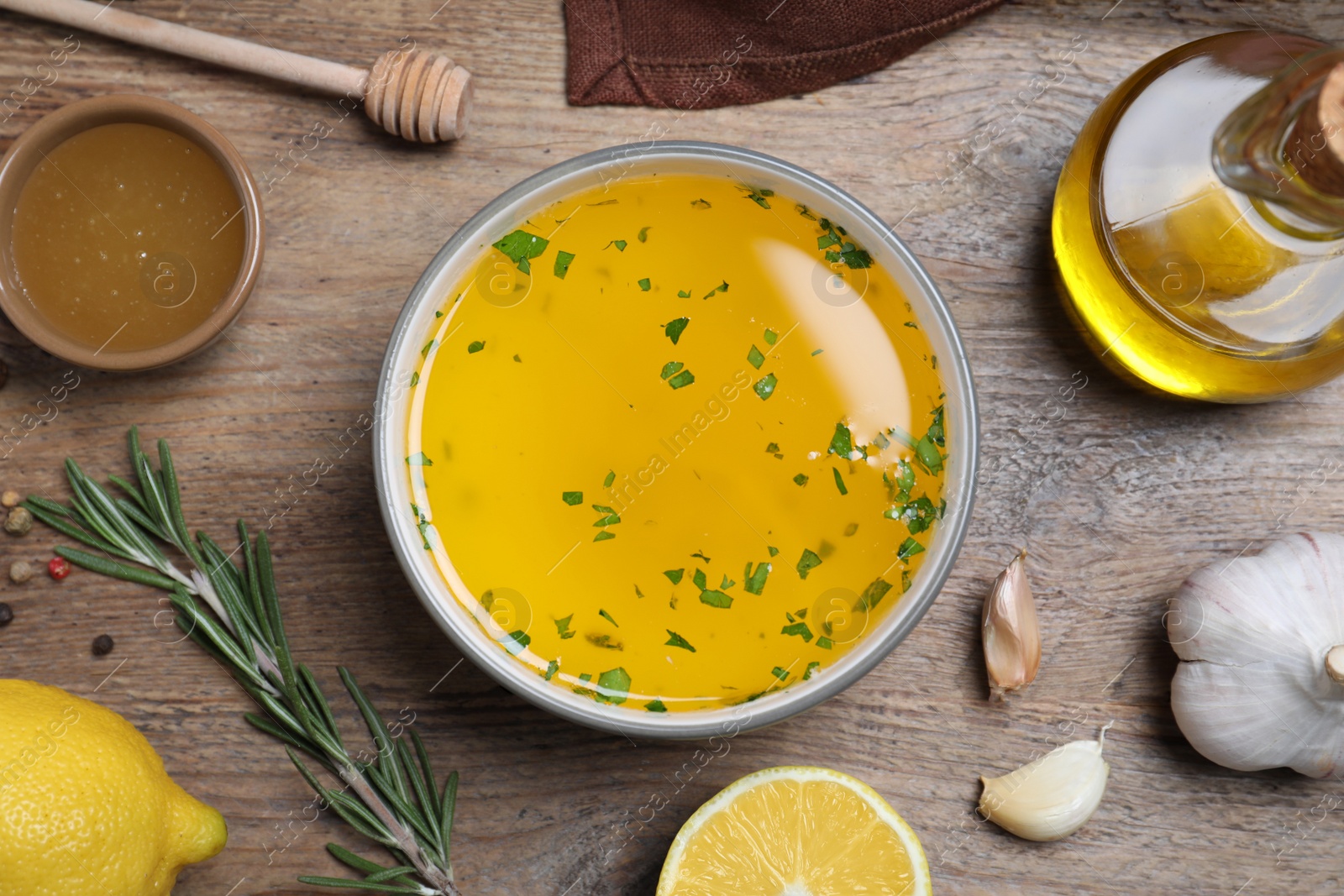 Photo of Bowl with lemon sauce and ingredients on wooden table, flat lay. Delicious salad dressing