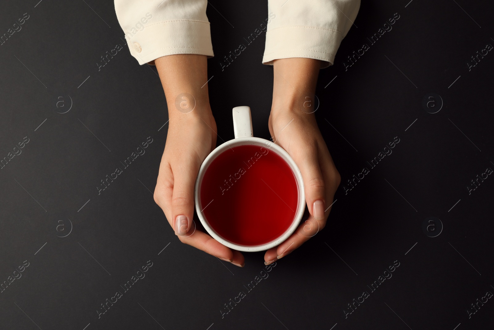 Photo of Woman with cup of tea on black background, top view