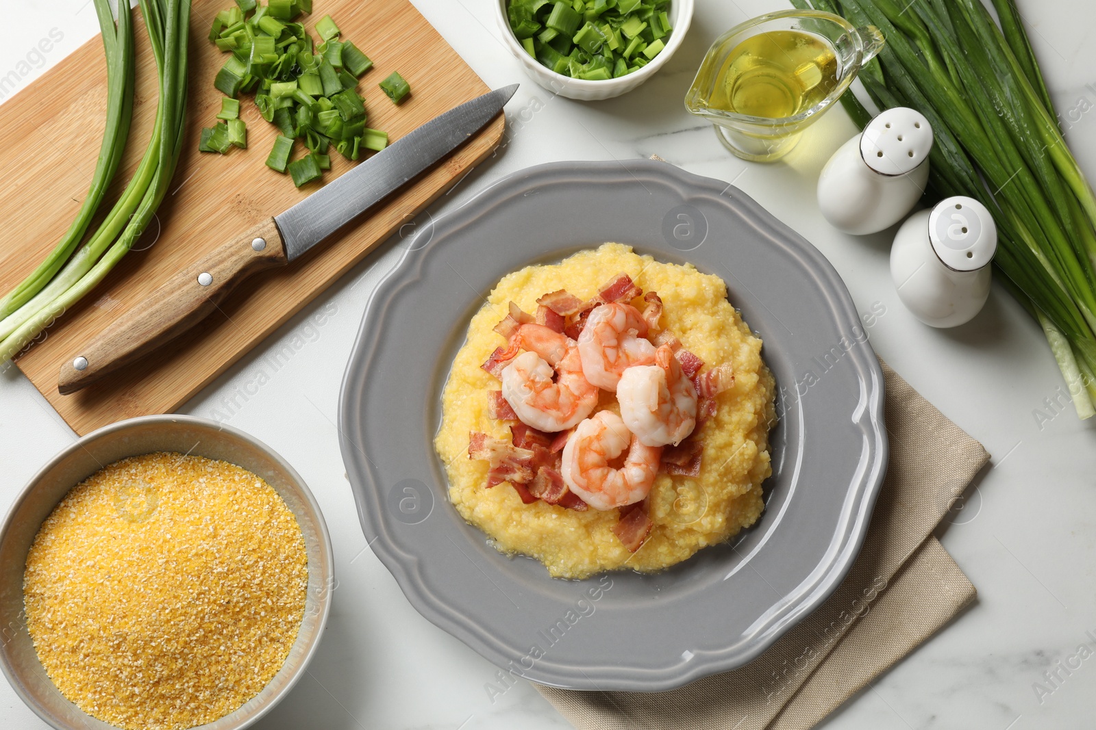 Photo of Plate with fresh tasty shrimps, bacon, grits and green onion on white marble table, flat lay