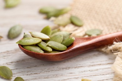 Spoon with peeled seeds on light wooden table, closeup