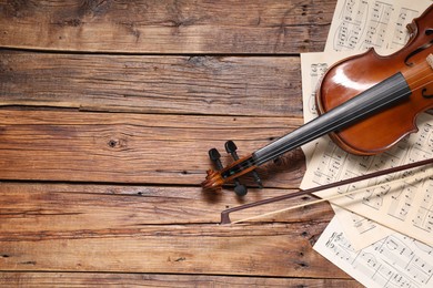 Photo of Violin, bow and music sheets on wooden table, top view. Space for text