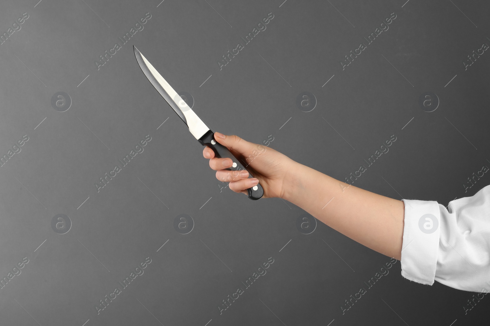 Photo of Woman holding carving knife on grey background, closeup. Space for text