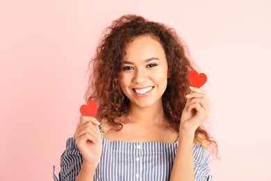 African-American woman with paper hearts on color background