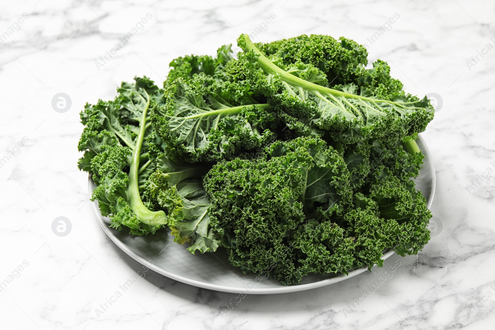 Photo of Fresh green kale leaves on white marble table