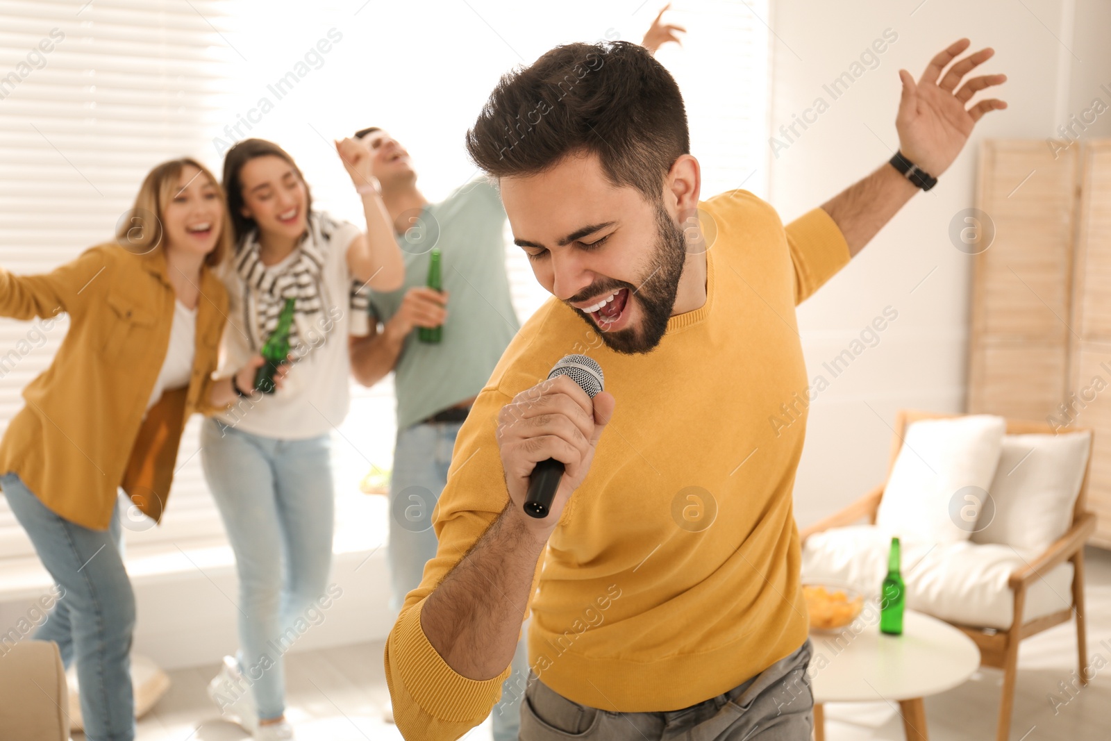 Photo of Young man singing karaoke with friends at home