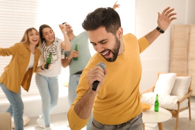Young man singing karaoke with friends at home