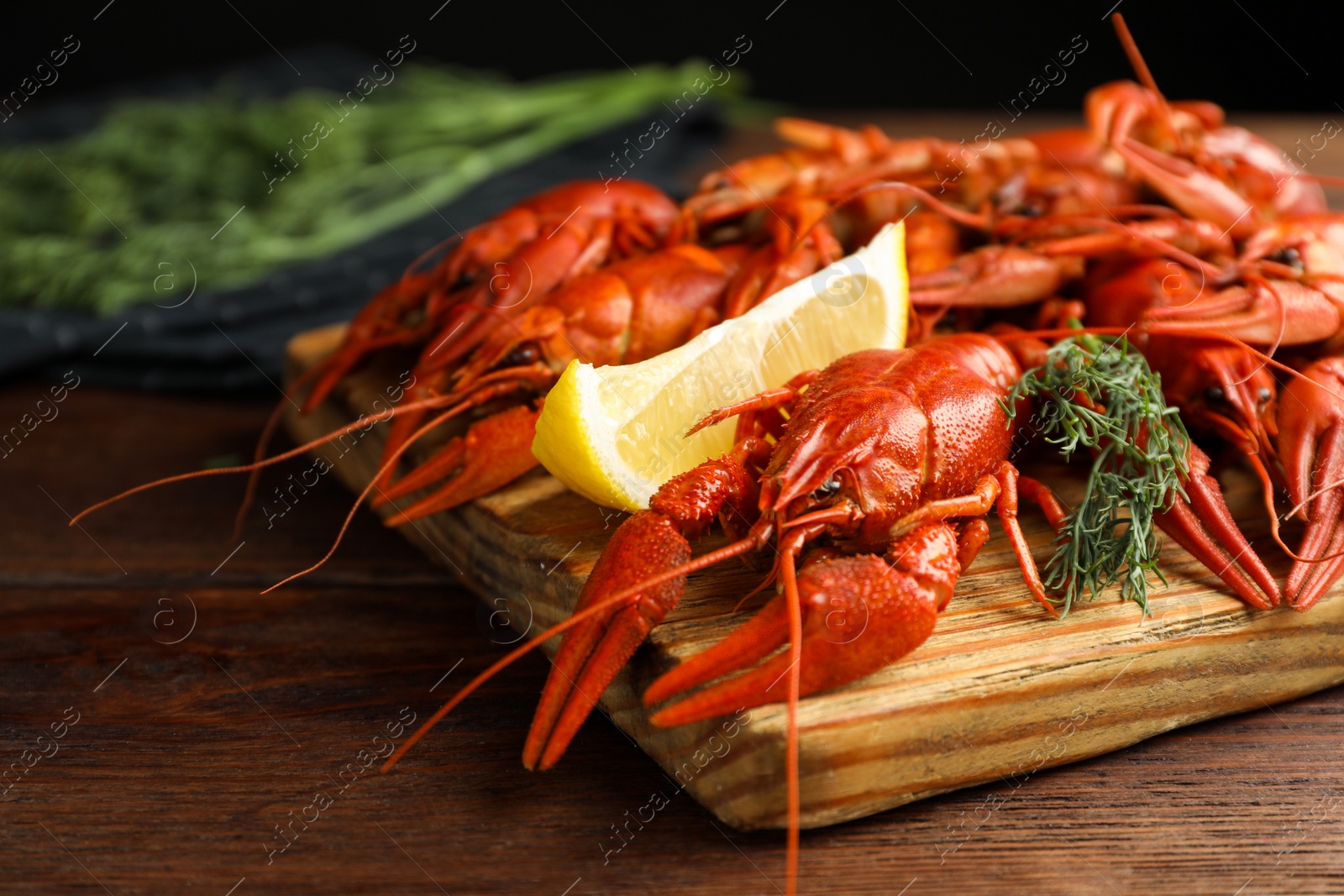 Photo of Delicious boiled crayfishes with lemon and dill on wooden table, closeup