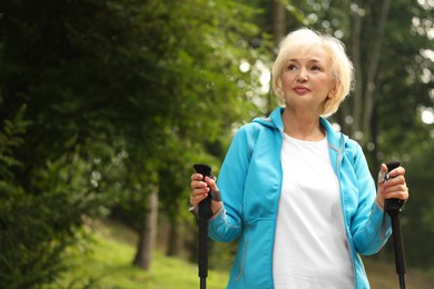 Senior woman with Nordic walking poles outdoors, space for text