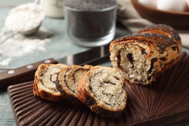 Photo of Board with freshly baked poppy seed roll on table