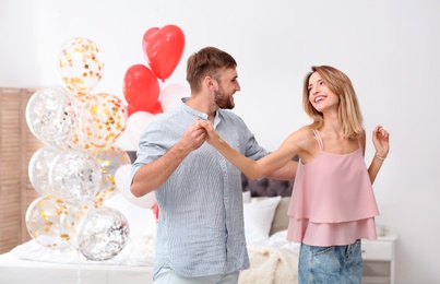 Young couple with air balloons in bedroom. Celebration of Saint Valentine's Day