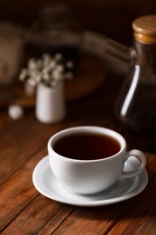 Photo of Cup with delicious tea on wooden table