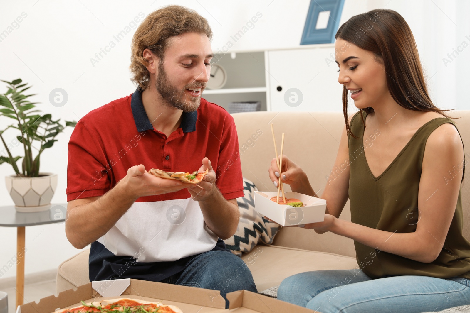 Photo of Young couple having lunch in living room. Food delivery