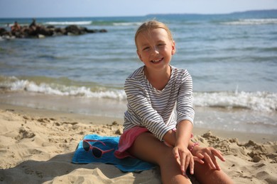 Happy little girl on sandy beach near sea